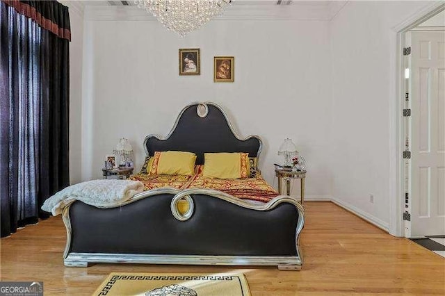 bedroom featuring an inviting chandelier, baseboards, ornamental molding, and wood finished floors
