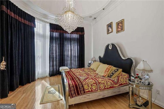 bedroom with crown molding, wood finished floors, and a notable chandelier