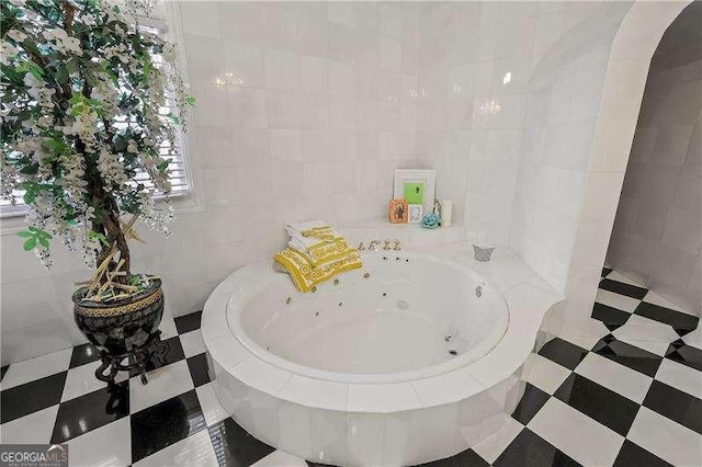 full bathroom with tile patterned floors, a whirlpool tub, and tile walls
