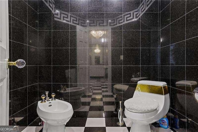 bathroom featuring tile walls, toilet, and a bidet