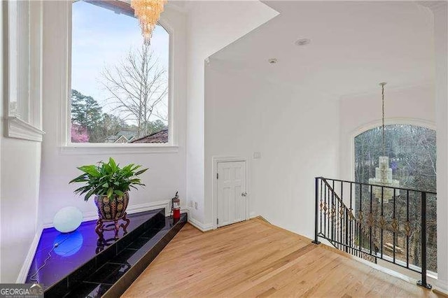 hall with an upstairs landing, a notable chandelier, and wood finished floors