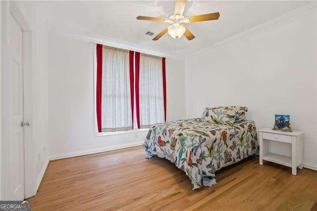 bedroom featuring a ceiling fan, wood finished floors, baseboards, and ornamental molding