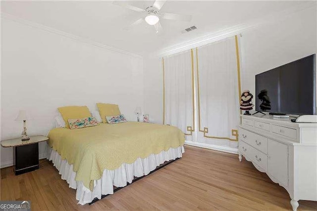bedroom featuring light wood-style flooring, ceiling fan, ornamental molding, and visible vents