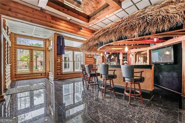 bar with a bar, granite finish floor, and rustic walls