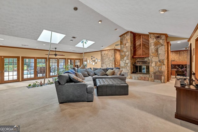 living room with carpet, a skylight, recessed lighting, vaulted ceiling, and a stone fireplace