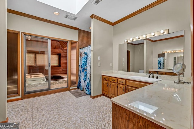 bathroom featuring a skylight, crown molding, vanity, baseboards, and recessed lighting
