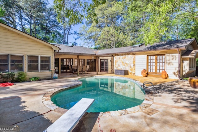 swimming pool with french doors, a patio, and a diving board