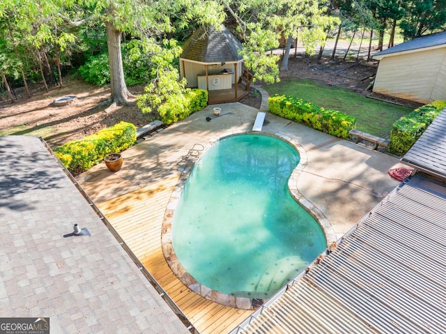 swimming pool with a patio, a diving board, and an outbuilding