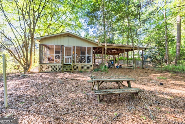 rear view of property featuring a sunroom and fence