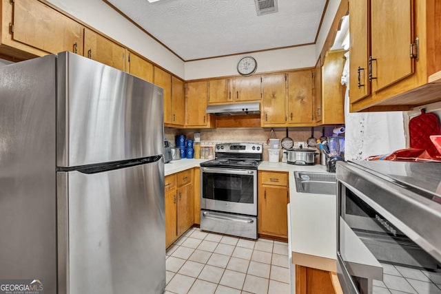 kitchen featuring stainless steel appliances, light tile patterned floors, light countertops, brown cabinets, and a sink
