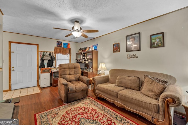 living room featuring ceiling fan, wood finished floors, a textured ceiling, and crown molding