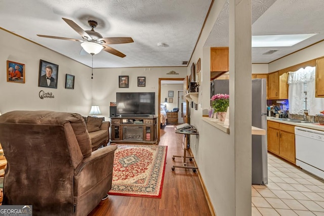 living room with a ceiling fan, a textured ceiling, and light wood-style flooring