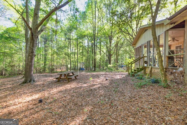 view of yard with a ceiling fan and a sunroom