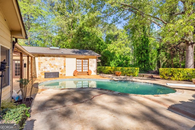 view of pool with a patio area, view of wooded area, and french doors