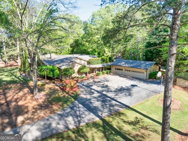 ranch-style house with driveway, a chimney, and a garage