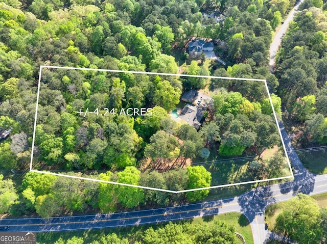 aerial overview of property's location with property parcel outlined and a forest
