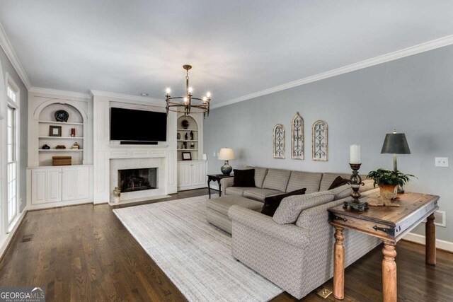 6201 Neely Farm Dr, Peachtree Corners, GA 30092 - living room with a chandelier, dark wood-style flooring, crown molding, built in shelves, and a fireplace