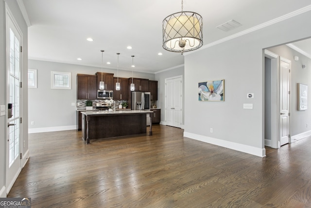 kitchen with dark wood-style floors, light countertops, dark brown cabinets, a center island with sink, and stainless steel appliances