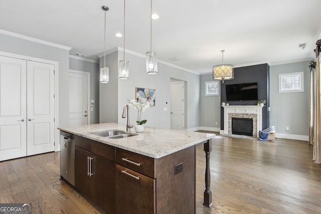 kitchen featuring dark wood-style flooring, a kitchen breakfast bar, a stone fireplace, a sink, and hanging light fixtures