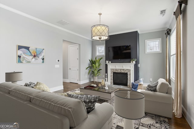 living room with dark wood-type flooring, ornamental molding, a stone fireplace, and visible vents