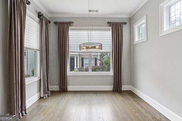 empty room featuring wood finished floors, baseboards, visible vents, and plenty of natural light