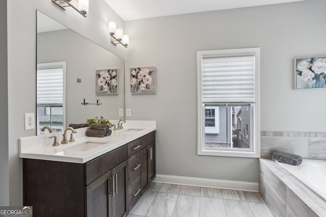 full bath featuring a garden tub, double vanity, a sink, and baseboards
