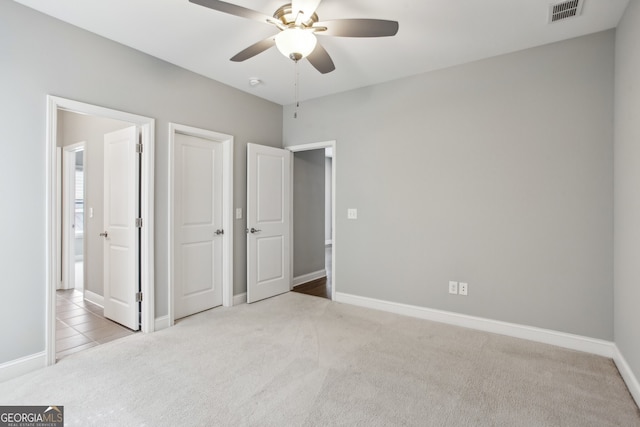 unfurnished bedroom with a ceiling fan, baseboards, carpet, and visible vents