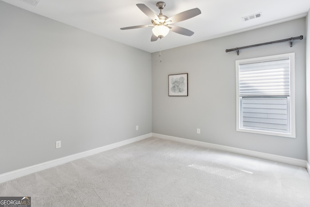 carpeted spare room featuring visible vents, baseboards, and ceiling fan