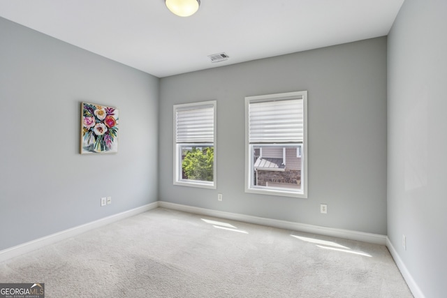 carpeted empty room with visible vents and baseboards