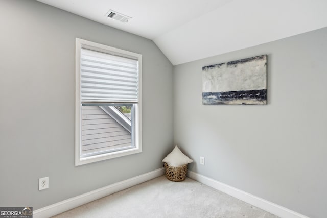 empty room with carpet, visible vents, baseboards, and vaulted ceiling