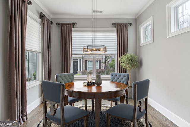 dining room featuring wood finished floors, visible vents, and plenty of natural light