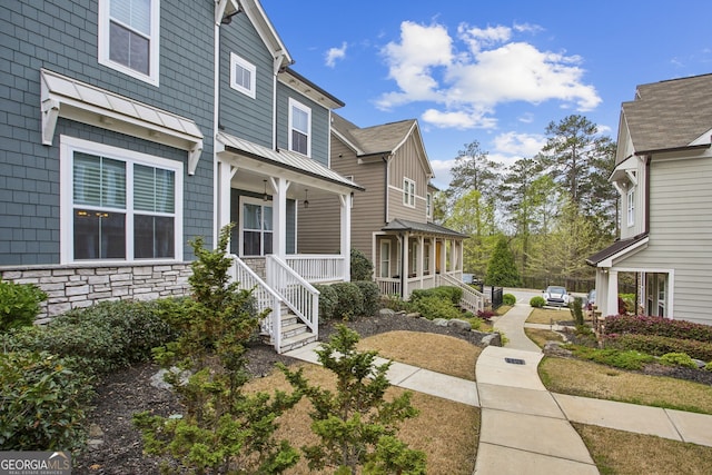 view of home's exterior featuring covered porch, stone siding, a standing seam roof, and metal roof
