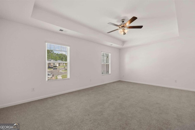 empty room with plenty of natural light, carpet floors, a raised ceiling, and ceiling fan