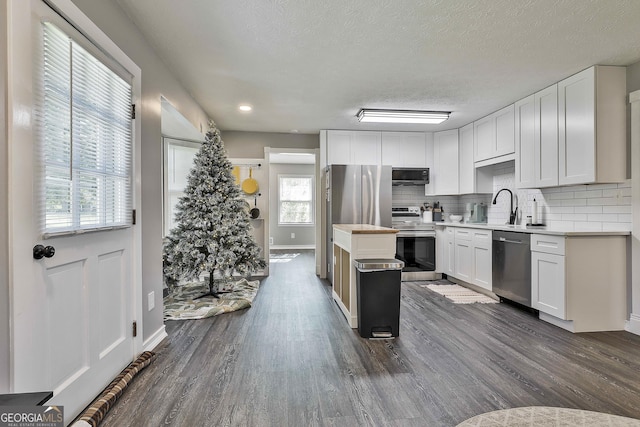 325 Sweetbriar Ln, Griffin, GA 30224 - kitchen with a center island, appliances with stainless steel finishes, light countertops, decorative backsplash, and dark wood-style floors