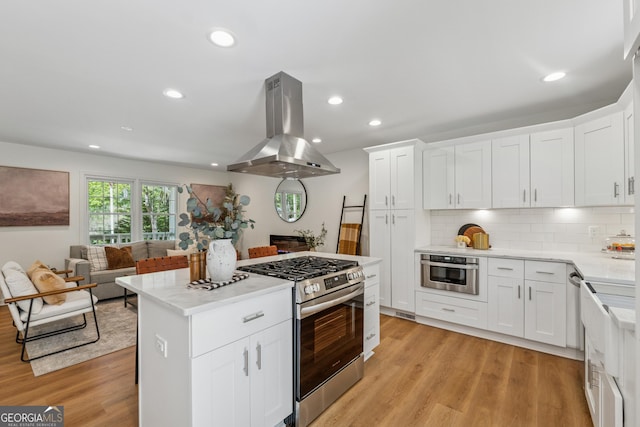 388 Pine Trl, Canton, GA 30115 - kitchen with island range hood, tasteful backsplash, light wood-style flooring, and appliances with stainless steel finishes