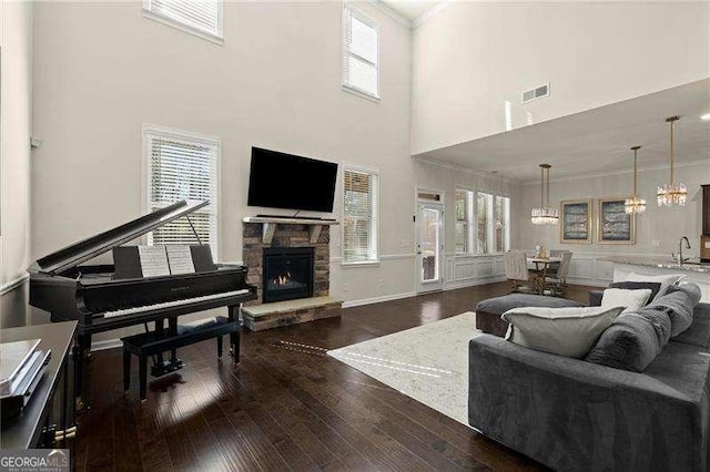 living area with visible vents, plenty of natural light, a fireplace, crown molding, and dark wood finished floors