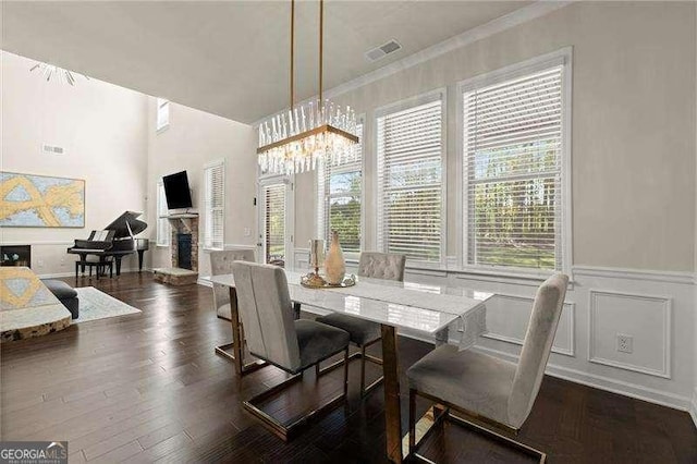 dining space featuring a chandelier, a fireplace, wood finished floors, and a healthy amount of sunlight