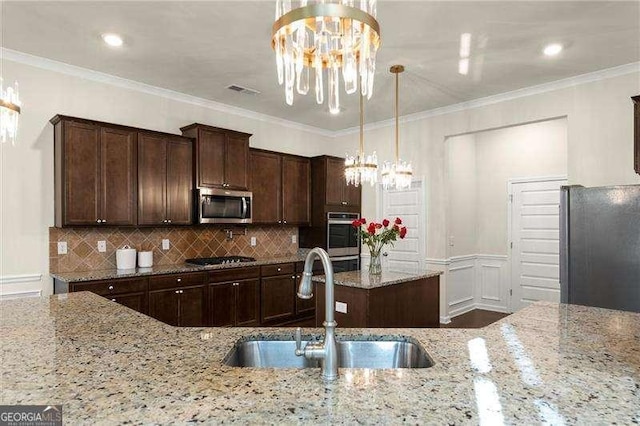 kitchen featuring a sink, a notable chandelier, ornamental molding, and stainless steel appliances