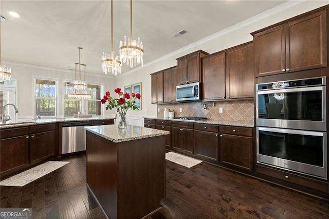 kitchen with an inviting chandelier, light stone countertops, visible vents, appliances with stainless steel finishes, and a sink