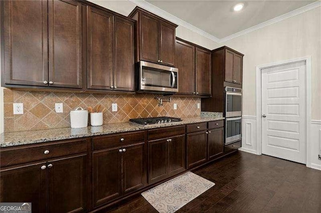 kitchen featuring light stone countertops, ornamental molding, appliances with stainless steel finishes, dark wood-style flooring, and backsplash