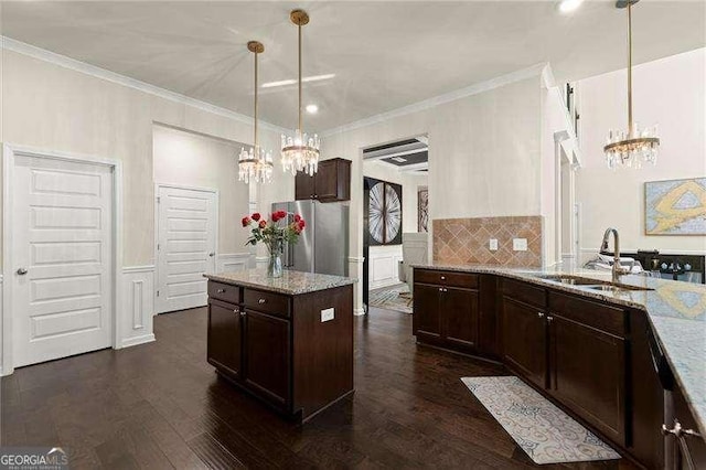 kitchen with a sink, freestanding refrigerator, a chandelier, and dark brown cabinetry