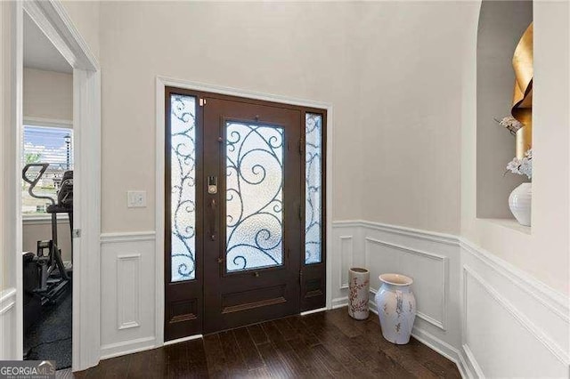 entrance foyer featuring a decorative wall, dark wood-style flooring, and a wainscoted wall