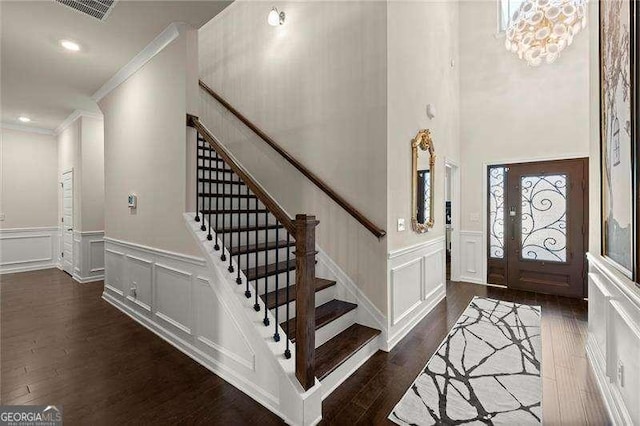 entrance foyer featuring visible vents, a decorative wall, ornamental molding, stairs, and dark wood-type flooring