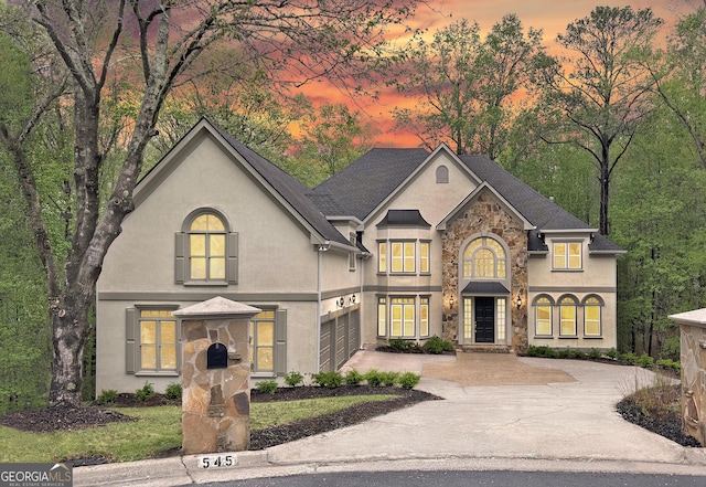 view of front of house with concrete driveway, stucco siding, and stone siding