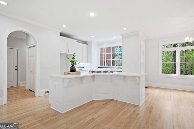 kitchen featuring crown molding, light countertops, and light wood finished floors