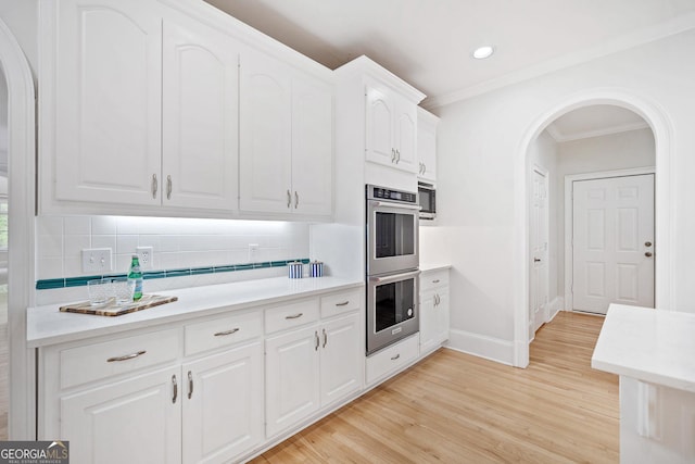 kitchen with arched walkways, tasteful backsplash, double oven, and baseboards