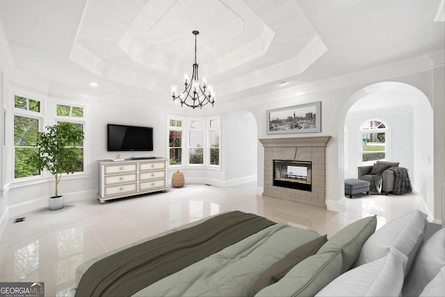 bedroom with a raised ceiling, tile patterned floors, baseboards, and arched walkways
