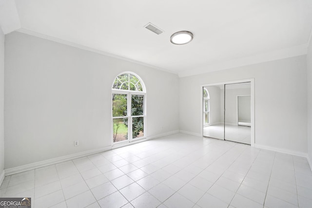 unfurnished bedroom with ornamental molding, visible vents, baseboards, and a closet