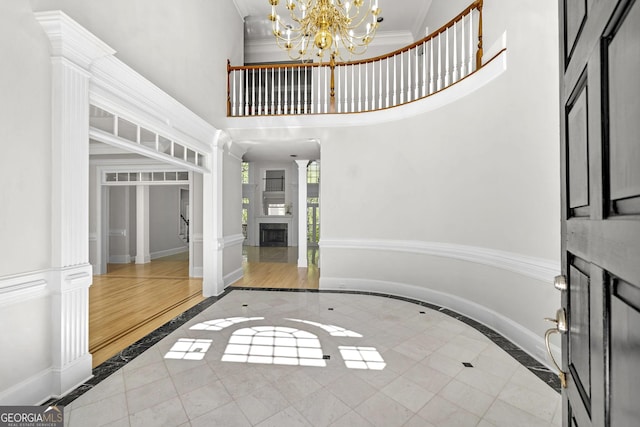 foyer entrance with crown molding, baseboards, an inviting chandelier, and a towering ceiling