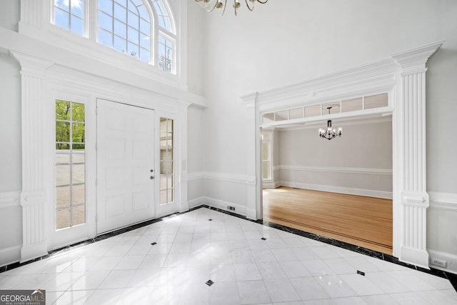 foyer with a high ceiling, plenty of natural light, a chandelier, and baseboards